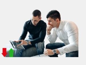 Two men examining a stock chart on a tablet, discussing potential investment moves.