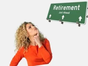 woman in an orange sweater thinking about retirement with a road sign that reads "Retirement Just Ahead."