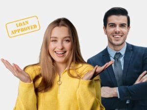 A smiling woman in a yellow sweater stands with a confident businessman behind her, and a “Loan Approved” stamp is visible