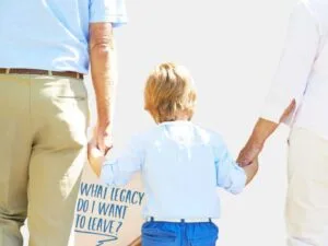 Financial Legacy: Grandparents holding hands with their grandchild, walking together with a sign that reads, "What legacy do I want to leave?