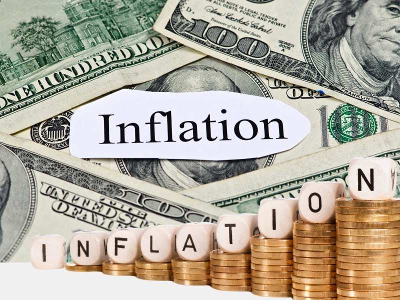 Stacks of U.S. dollar bills with the word 'Inflation' and coins spelling 'INFLATION,' symbolizing rising prices and inflation-linked bonds.